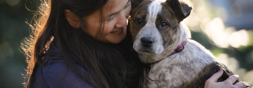 Girl hugging dog looking at the camera