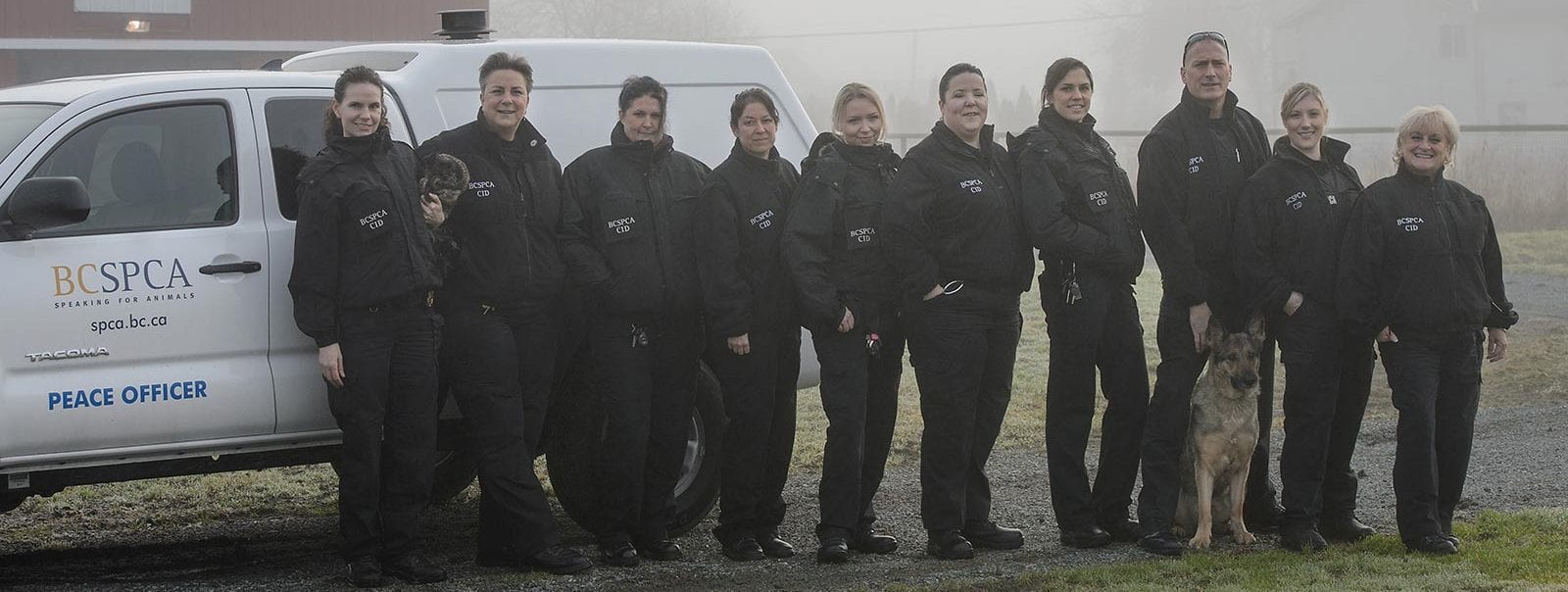 Cruelty investigative Department staff in uniform group shot with a dog in front of BC SPCA truck